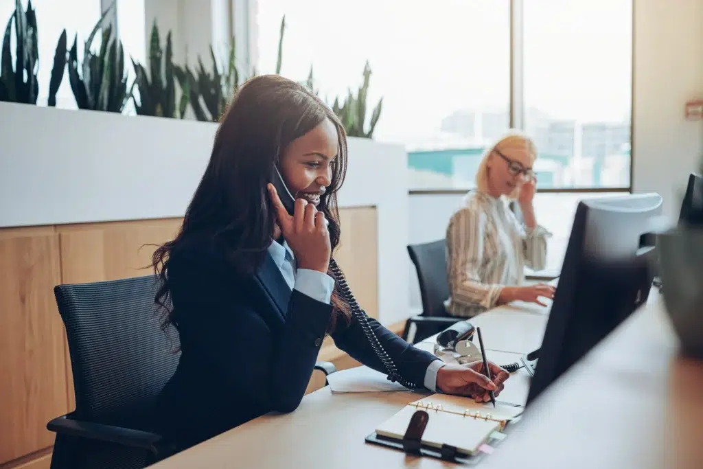 Image of a professional engaged in a sales call with a client, using a laptop and notes