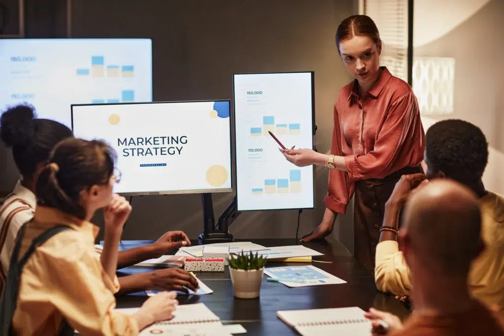 Image of a team in a meeting discussing marketing strategy with charts and notes.