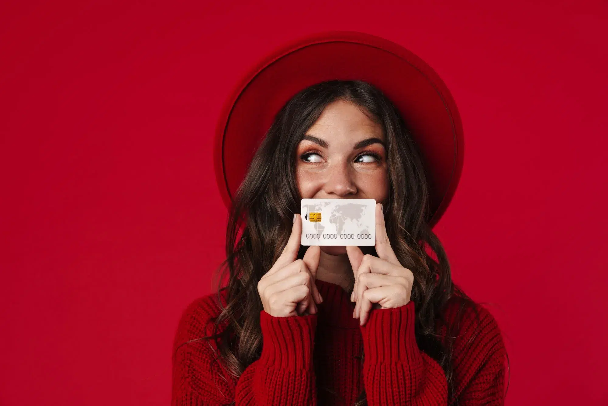 Woman in red hat holding a credit card and smiling, representing emotional appeal in marketing